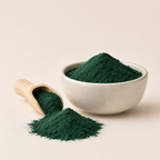 tamsiai žali spirulinos milteliai keraminiame dubenėlyje ir mediniame semtuvėlyje